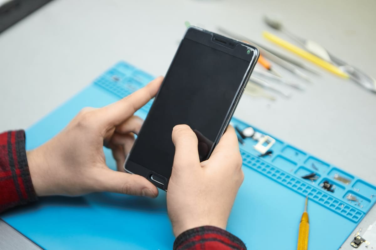 A technician testing a smartphone to find a fault