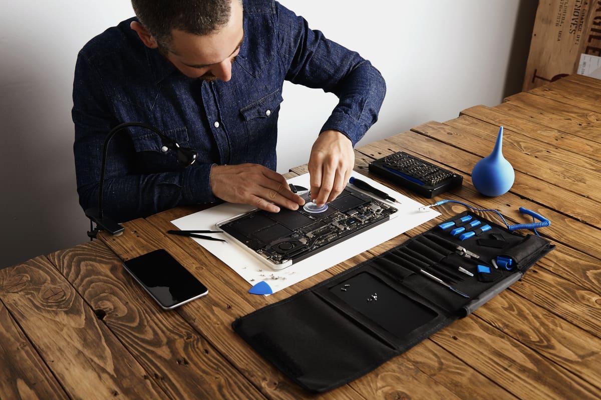 A technician removing battery cells from a broken laptop