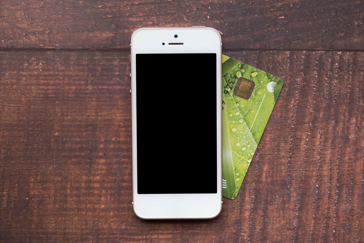 A smartphone next to a credit card, seen from above