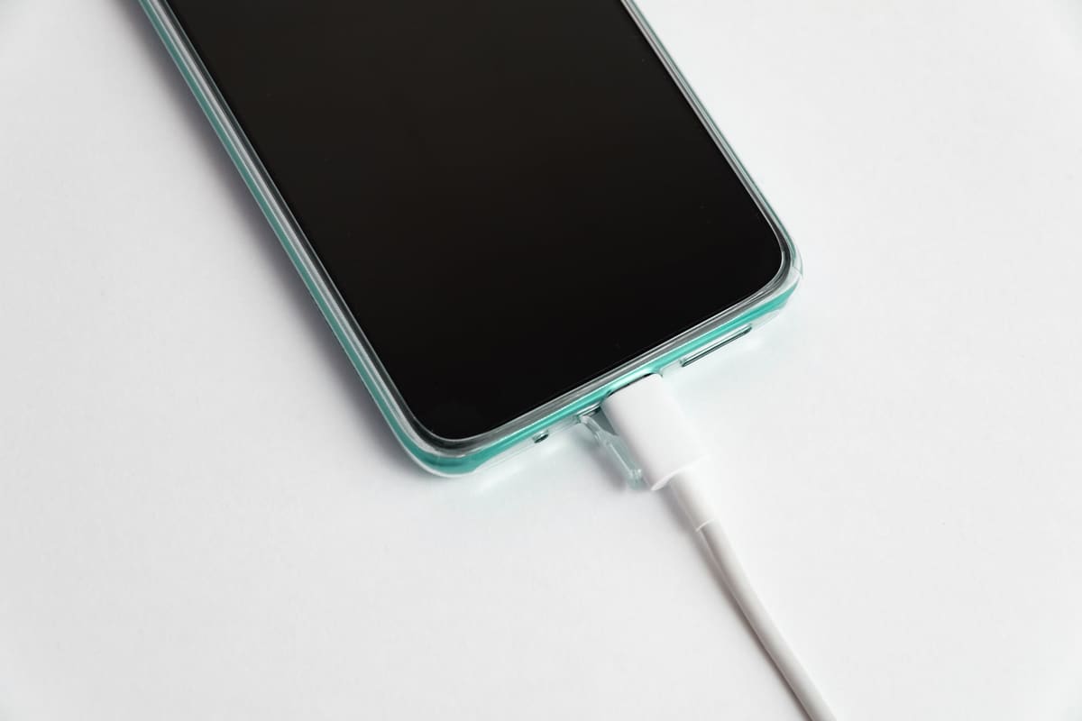 A smartphone connected to a USB-C charging cable