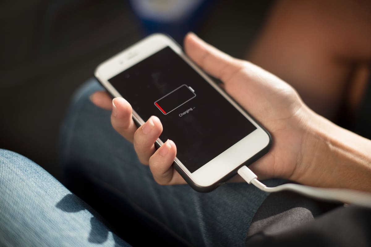 Hands plugging a charging cable into a smartphone