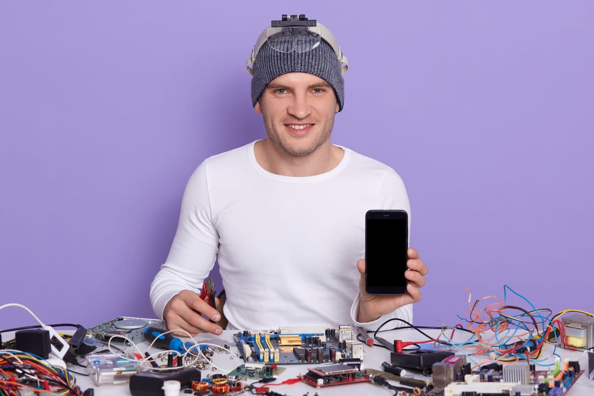 A repairman working on a broken smartphone with a blank screen