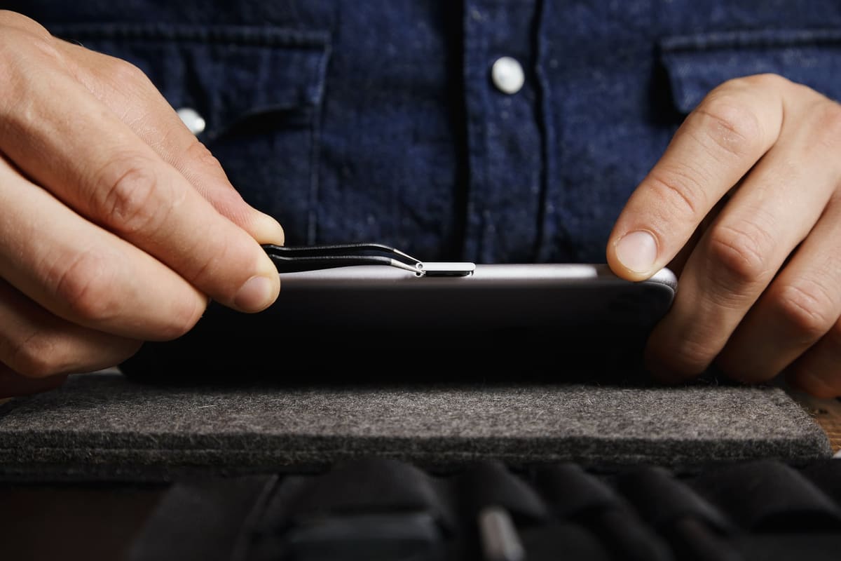 Tweezers pulling a SIM card tray out of a smartphone